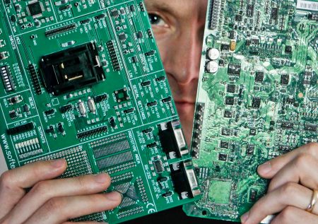 Security researcher Charlie Miller holds two automobile electronic control module circuit boards while posing in his home-office in Wildwood, Missouri